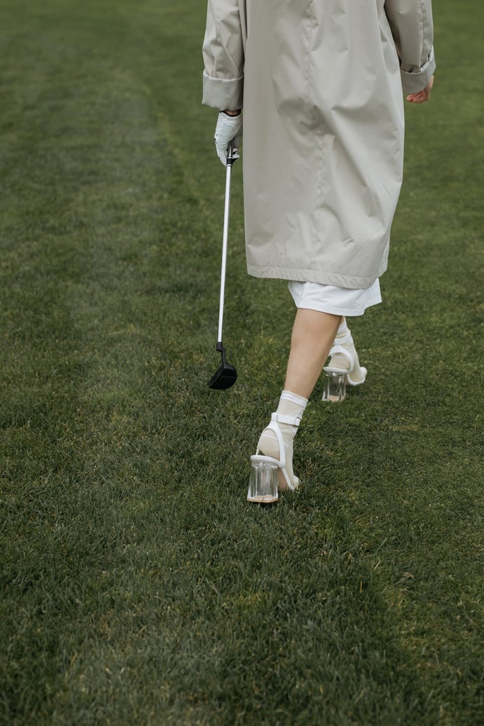 Persona con tacones altos caminando en el campo de golf